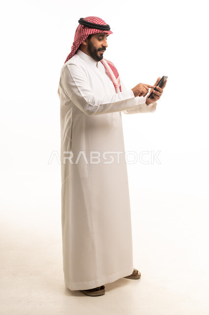 رجل سعودي بالزي التقليدي يستخدم الهاتف الذكي