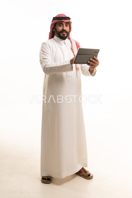 رجل سعودي مع جهاز لوحي بالزي التقليدي