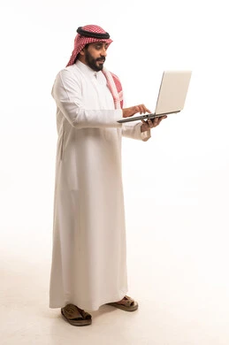 رجل سعودي بالزي التقليدي يستخدم الكمبيوتر المحمول