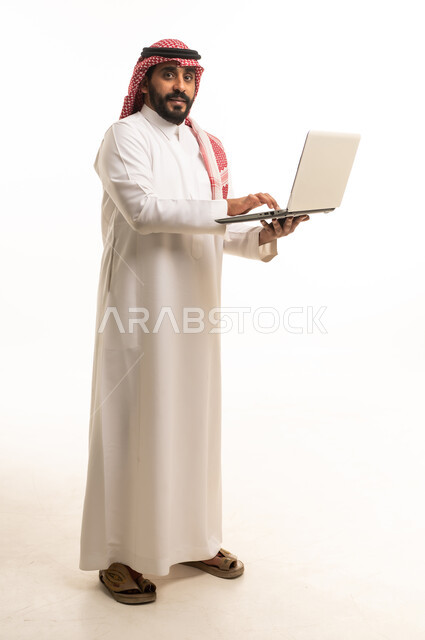 رجل سعودي بالزي التقليدي يحمل حاسوب محمول