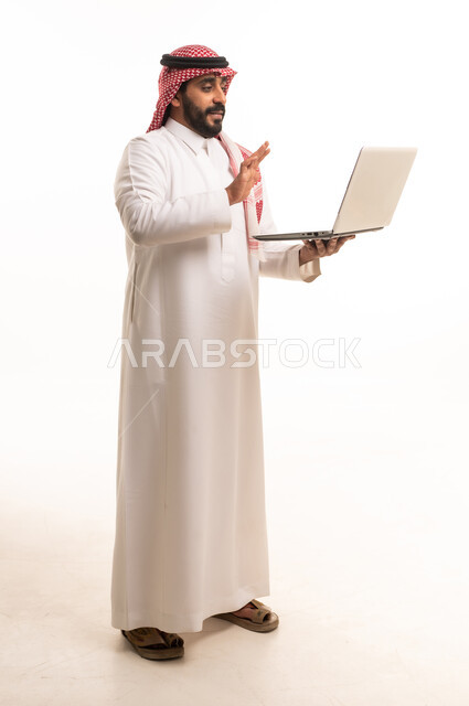 رجل سعودي بالزي التقليدي يستخدم الحاسوب المحمول
