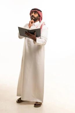 رجل سعودي بالزي التقليدي يحمل كتاباً