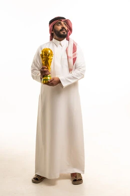 رجل سعودي بالزي التقليدي يحمل كأساً ذهبية