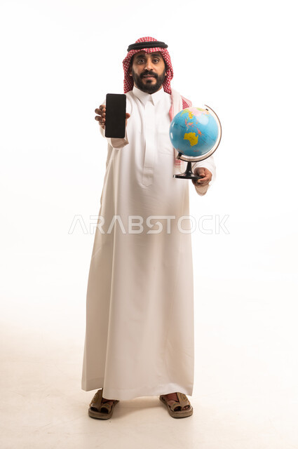 رجل سعودي مع هاتف ذكي ومجسم الكرة الأرضية