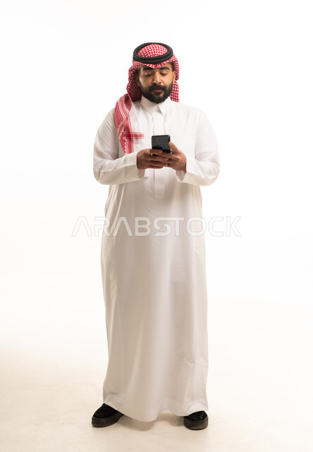 Saudi Man in Traditional Thobe Using Smartphone