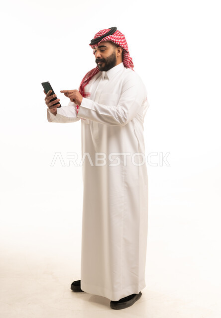 Saudi Man in Traditional Thobe Using Smartphone