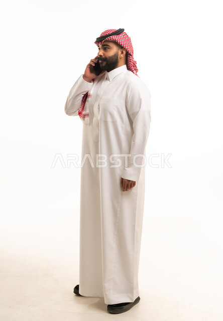 رجل سعودي بالثوب التقليدي يستخدم الهاتف الذكي