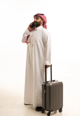 رجل سعودي مع حقيبة سفر يتحدث بالهاتف المحمول خلفية بيضاء