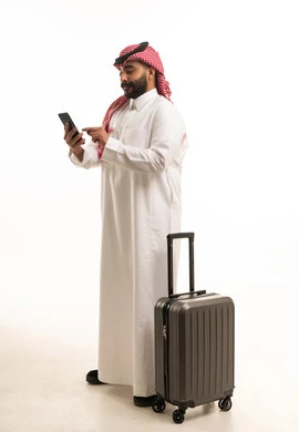 رجل سعودي مع حقيبة سفر يستخدم الهاتف