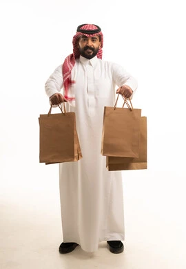 رجل سعودي يحمل أكياس تسوق بالزي التقليدي