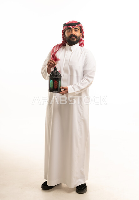 رجل سعودي يحمل فانوس رمضان بخلفية بيضاء