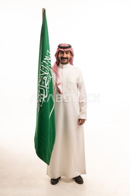 رجل سعودي يحمل علم المملكة العربية السعودية بخلفية بيضاء