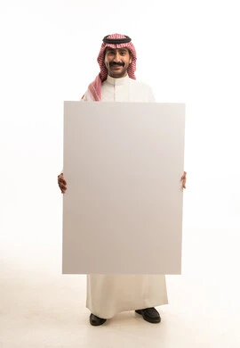 رجل سعودي يحمل لوحة بيضاء فارغة في الاستوديو