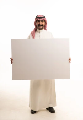 رجل سعودي يحمل لوحة بيضاء فارغة في الاستوديو