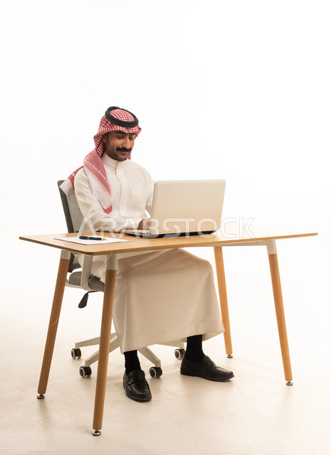 رجل سعودي يعمل على الكمبيوتر المحمول في المكتب