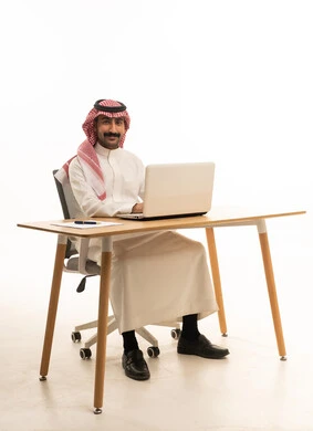 Saudi Man in Traditional Thobe Working on Laptop