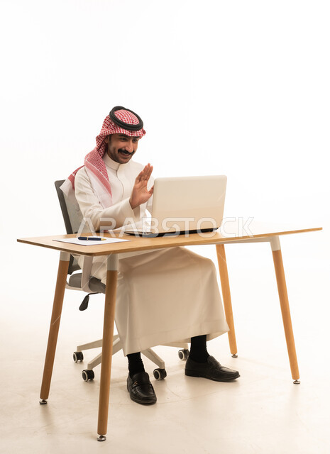 رجل سعودي بالزي التقليدي يستخدم الحاسوب لمكالمة فيديو