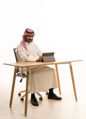 رجل سعودي يستخدم جهاز لوحي على مكتب عمل
