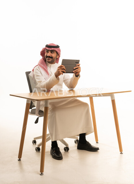 رجل أعمال سعودي يستخدم جهاز لوحي في مكتب استوديو