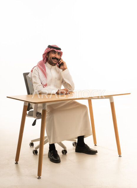 Saudi Man in Traditional Dress Using Smartphone at Desk