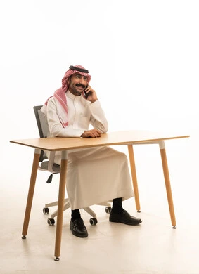 رجل سعودي بالزي التقليدي يتحدث عبر الهاتف في المكتب