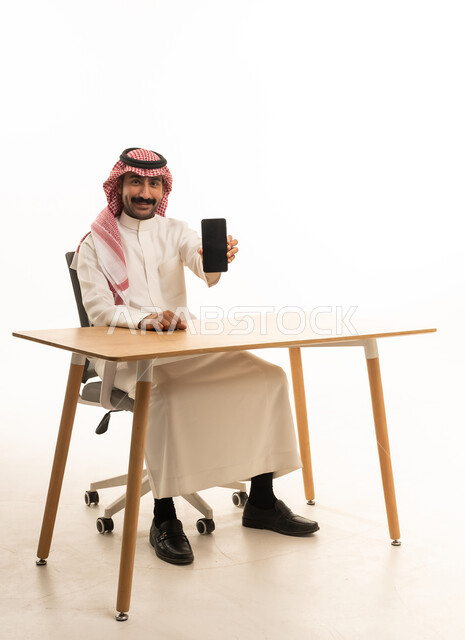 رجل سعودي يحمل هاتف ذكي في استوديو