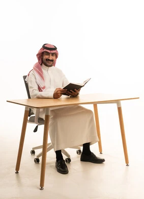 Saudi Man Sitting at Desk Reading Book