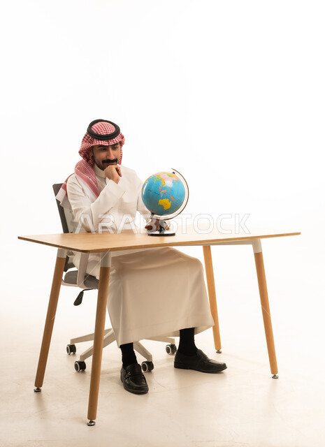 Saudi Man in Traditional Thobe Thinking with Globe