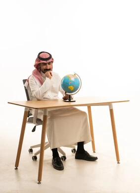 Saudi Man in Traditional Thobe Thinking with Globe