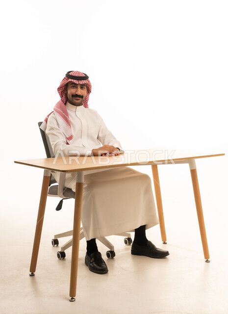 رجل سعودي يجلس على مكتب بالزي التقليدي