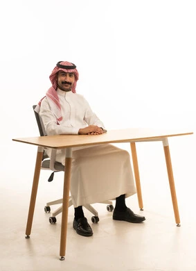 رجل سعودي يجلس على مكتب بالزي التقليدي