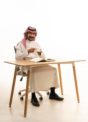 رجل سعودي على مكتب عمل مع فنجان قهوة