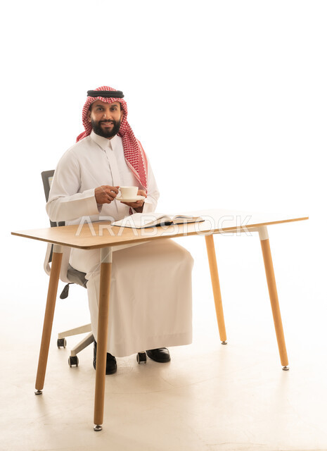 رجل سعودي بالزي التقليدي يجلس على مكتب عمل
