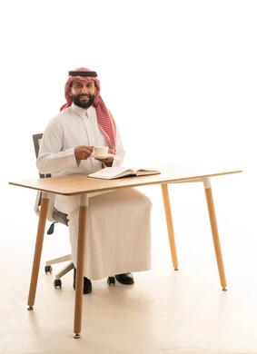 رجل سعودي بالزي التقليدي يجلس على مكتب عمل