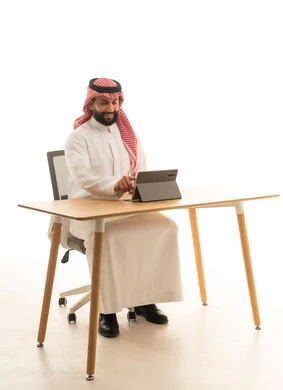 Saudi Man Using Tablet at Desk on White Background