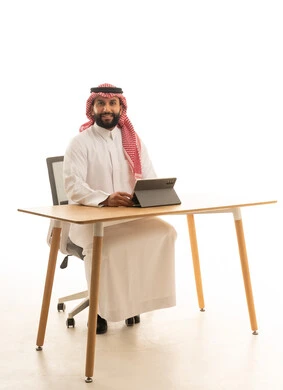 Saudi Man at Desk Using Digital Tablet White Background
