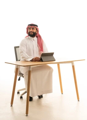 رجل سعودي باللباس التقليدي يعمل على جهاز لوحي