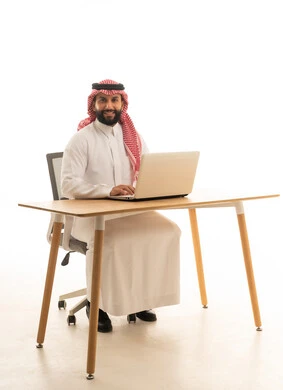رجل سعودي يعمل على حاسوب محمول في المكتب
