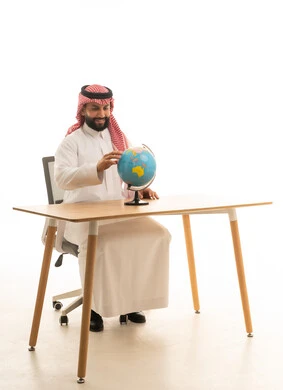 رجل سعودي بالثوب التقليدي مع مجسم الكرة الأرضية