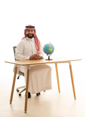رجل أعمال سعودي على مكتب مع مجسم الكرة الأرضية