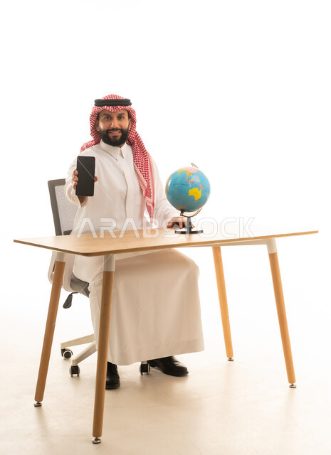 Saudi Man Holding Smartphone with Globe on Desk