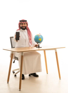 Saudi Man Holding Smartphone with Globe on Desk