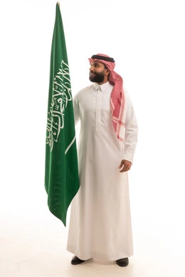 رجل سعودي يحمل العلم الوطني على خلفية بيضاء