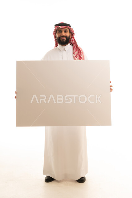 رجل سعودي يحمل لوحة بيضاء فارغة في الاستوديو