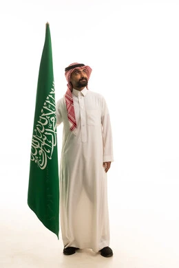 Saudi Man Holding National Flag in Traditional Thobe