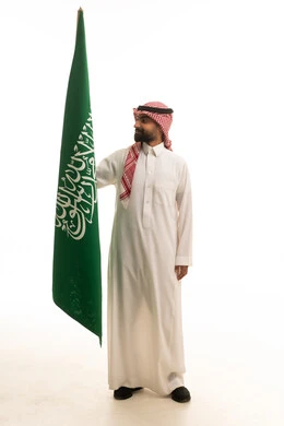 رجل سعودي يحمل العلم الوطني على خلفية بيضاء