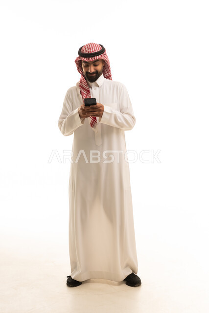 رجل سعودي بالثوب التقليدي يستخدم الهاتف الذكي