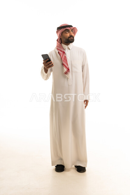 رجل سعودي بالزي التقليدي يستخدم الهاتف الذكي