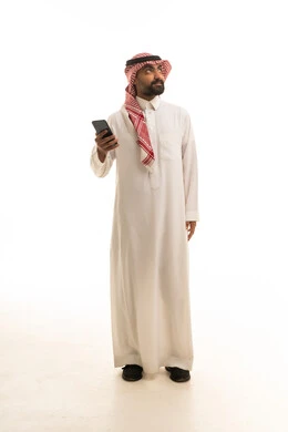 رجل سعودي بالزي التقليدي يستخدم الهاتف الذكي