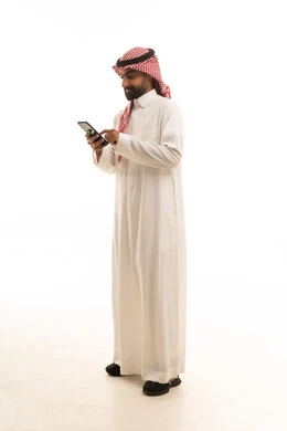 رجل سعودي بالثوب التقليدي يستخدم الهاتف الذكي